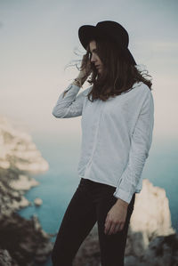 Young woman standing at beach against sky