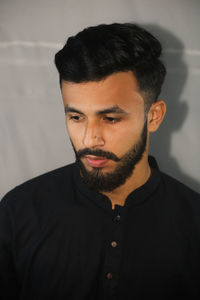 Portrait of young man against black background