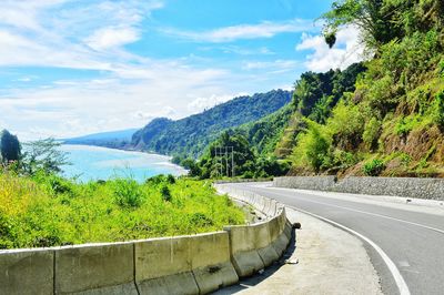 Scenic view of road by mountains against sky