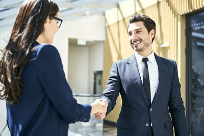 Smiling businessman and businesswoman shaking hands in office