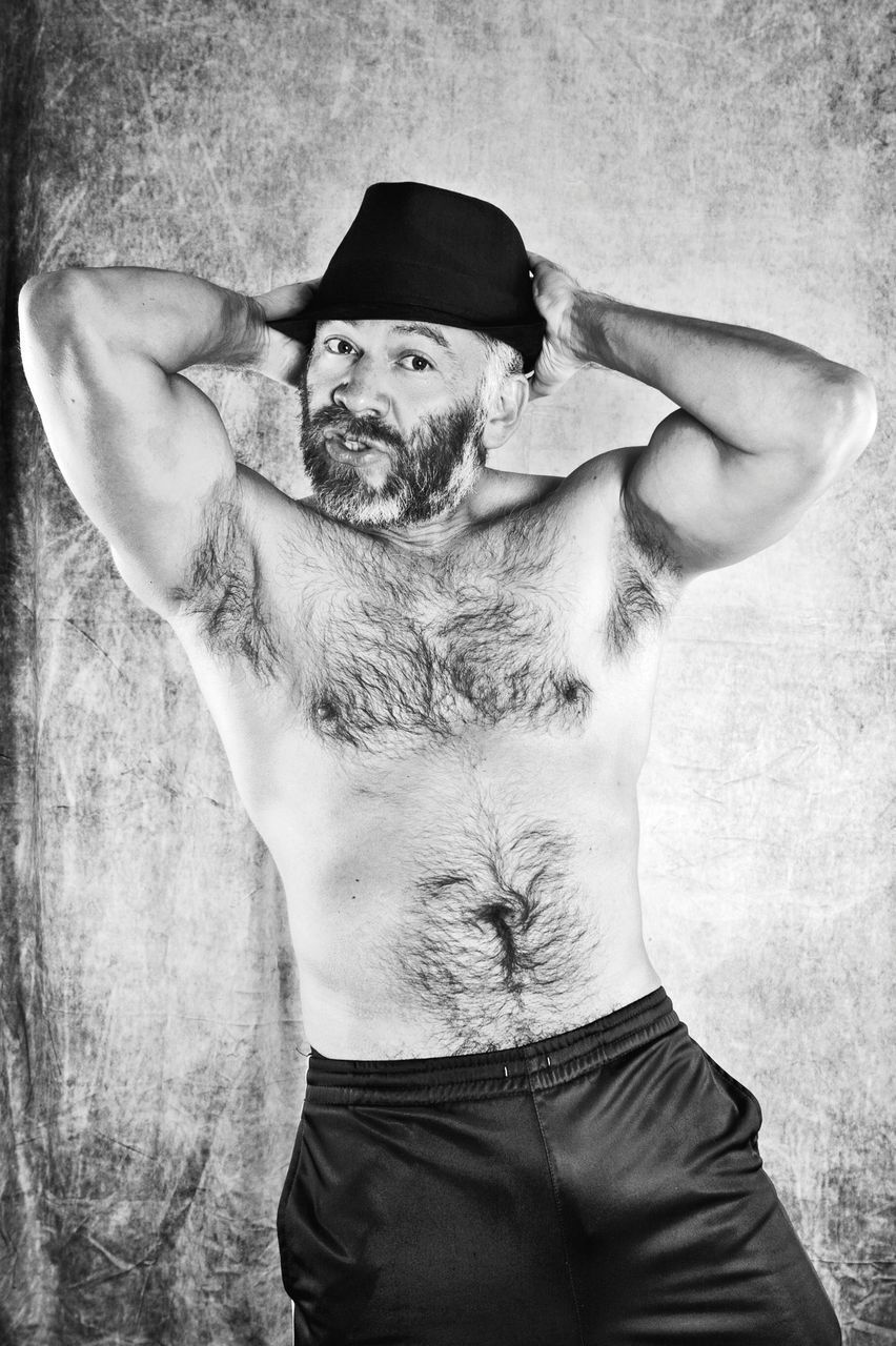 PORTRAIT OF SHIRTLESS MAN WEARING HAT STANDING AGAINST HUMAN FACE