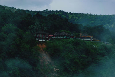 Building by trees in forest against sky