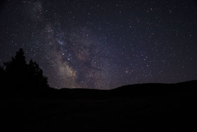 Low angle view of silhouette landscape against star field at night