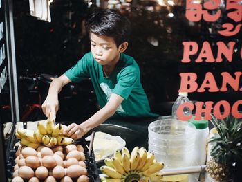 Boy cutting bananas at market for sale