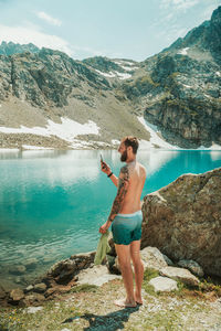 Full length of man standing on rock by lake