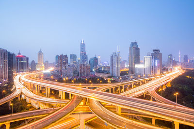 High angle view of light trails on road amidst buildings in city against sky