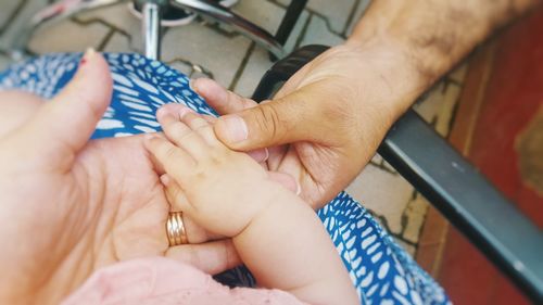 High angle view of baby hand holding hands