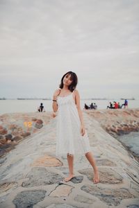 Woman standing on beach by sea against sky