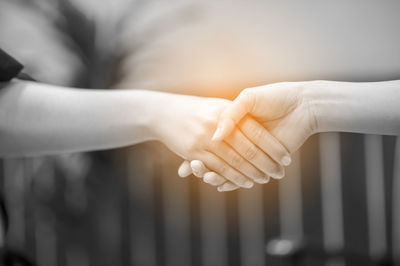 Close-up of friends shaking hands outdoors