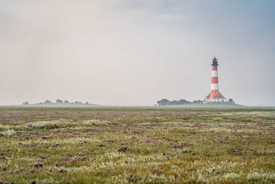 Lighthouse by sea against sky