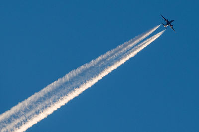 Low angle view of airplane flying against clear blue sky