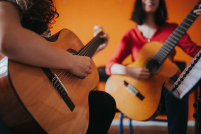 Friends practicing while playing guitar at home