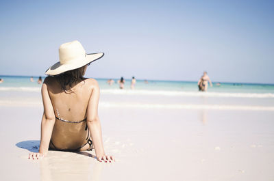 Rear view of woman sitting at beach