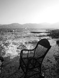 Abandoned chair on beach against clear sky