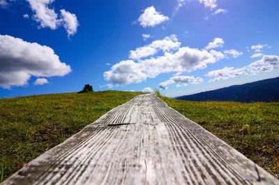 Surface level of dirt road on field against sky