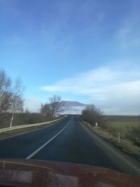 Road amidst trees against sky seen through car windshield