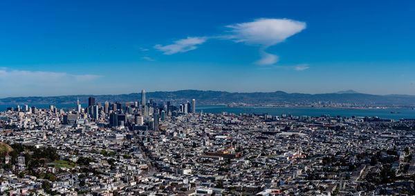 High angle view of city by sea against blue sky