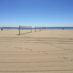 Pier on beach against blue sky