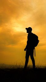 Silhouette man standing on field against sky during sunset