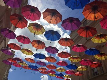 Low angle view of multi colored umbrellas hanging against sky