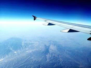 Aerial view of snowcapped mountains against blue sky