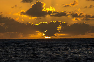 Scenic view of sea against dramatic sky during sunset