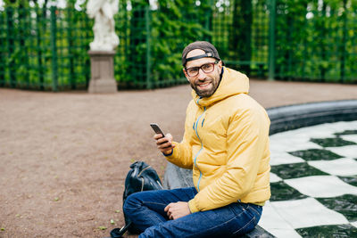 Young man using mobile phone while sitting outdoors