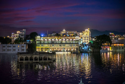 Illuminated buildings by river at night