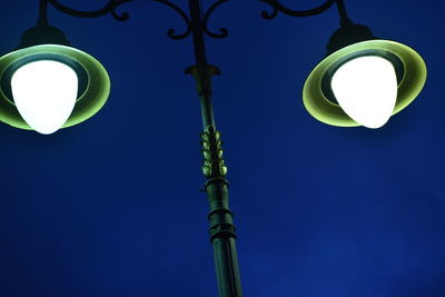 Low angle view of illuminated lamp against blue sky