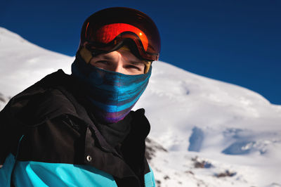 Portrait of a skier in the mountains without a ski mask with a scarf on his face, narrowing his eyes