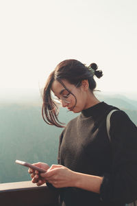 Side view of woman using mobile phone against white background