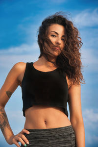 Young woman standing against blue sky