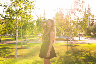 Portrait of smiling young woman standing against trees