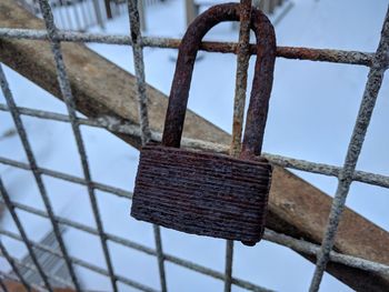 Rusty padlock hanging on fence