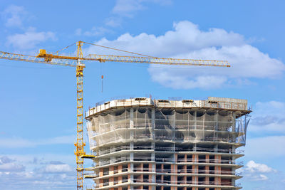 Tower crane on the background of the construction of a multi-storey high-rise residential building.