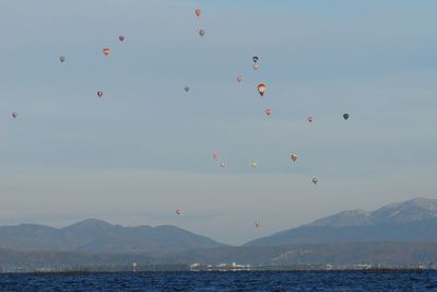 Scenic view of lake against sky with huge numbers of balloons