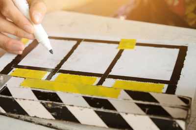 Close-up of cropped hand writing above film slate