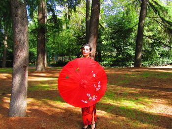 Portrait of man standing by tree trunk in forest