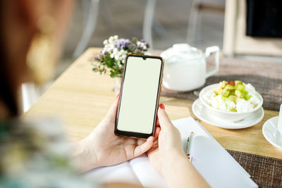 Midsection of person using mobile phone on table