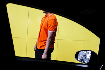 Midsection of man seen through car window