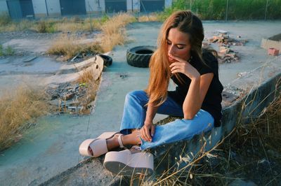 Young woman sitting on grass by water