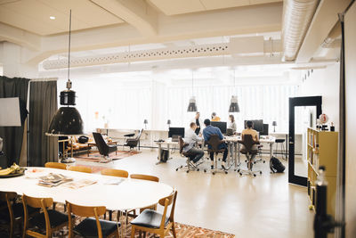 Software engineers discussing at desk against window in creative office