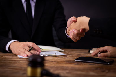 Midsection of man using smart phone on table