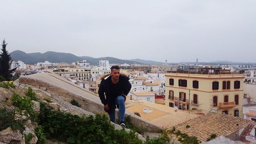 Man standing on rock against buildings