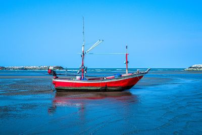 Fishing boat in sea against clear blue sky