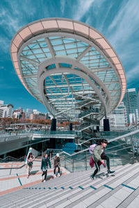 People in amusement park against sky in city