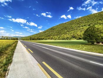 Empty road along landscape and against sky