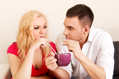 Loving couple sharing coffee from cup at home