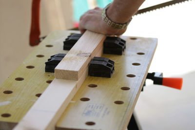 Cropped hand of carpenter cutting wood