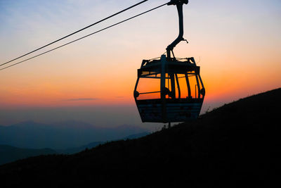 Silhouette of overhead cable car against sky during sunset